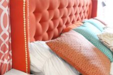 26 add a touch of color with a coral tufted headboard and decorative nails for a bold look