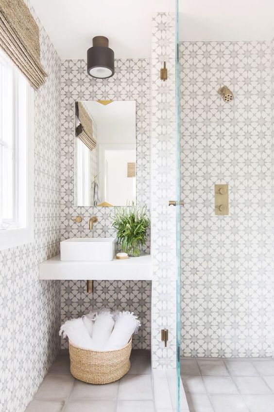 chic patterned mosaic tiles on the walls and neutral light grey ones on the floor plus brass accents