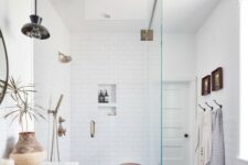 a beautiful mid-century modern bathroom with white subway and black hex tiles, a stained vanity, brass and black fixtures