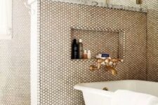 a chic bathroom with grey tiles and penny ones on the walls, a pony wall, brass touches and a vintage bathtub