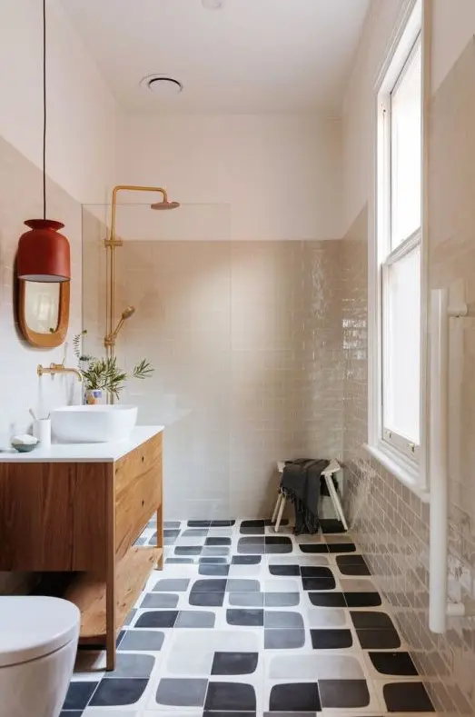 A mid century modern bathroom with grey and graphic black and white tiles, a stained vanity, white appliances and gold fixtures
