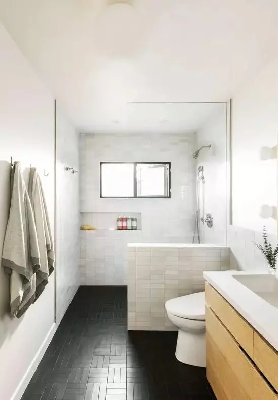 A modern bathroom with marble skinny tiles and black ones on the floor, a floating wooden vanity, a built in niche for storage