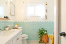 a modern beachy bathroom in neutrals, with aqua fishscale tiles, a tree stump, a large vanity and potted greenery