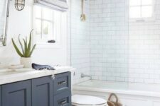 a nautical bathroom clad with white subway and navy hex tiles, a navy vanity, a shower space and a tub, navy shades