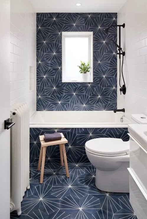 A small modern bathtoom with eye catchy hexagon tiles, white appliances and black fixtures