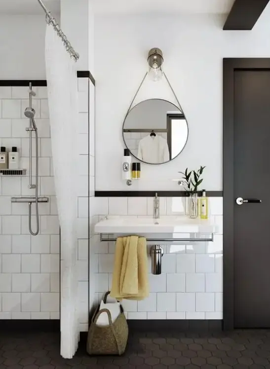 A stylish white and graphite grey mid century modern bathroom with grey hex tiles on the floor and a round mirror and a floating sink