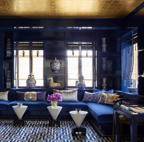 a bold and exquisite living room in electric blue spruced up with a gold ceiling and gold touches