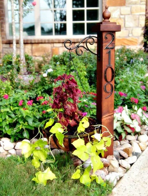 A garden post with a hanging planter and elegant metal house numbers is a stylish vintage inspired idea