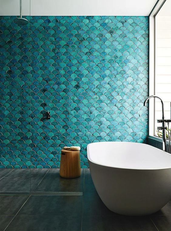 A turquoise fish scale tile statement wall makes the space feel mermaid like, and a serene tub adds to it