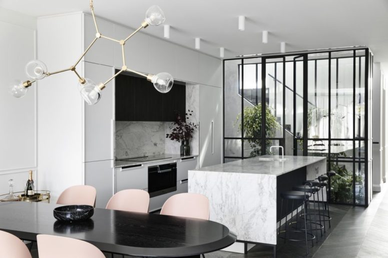 The kitchen is done in white and with white stone countertops and a backsplash, it flows into a dining space