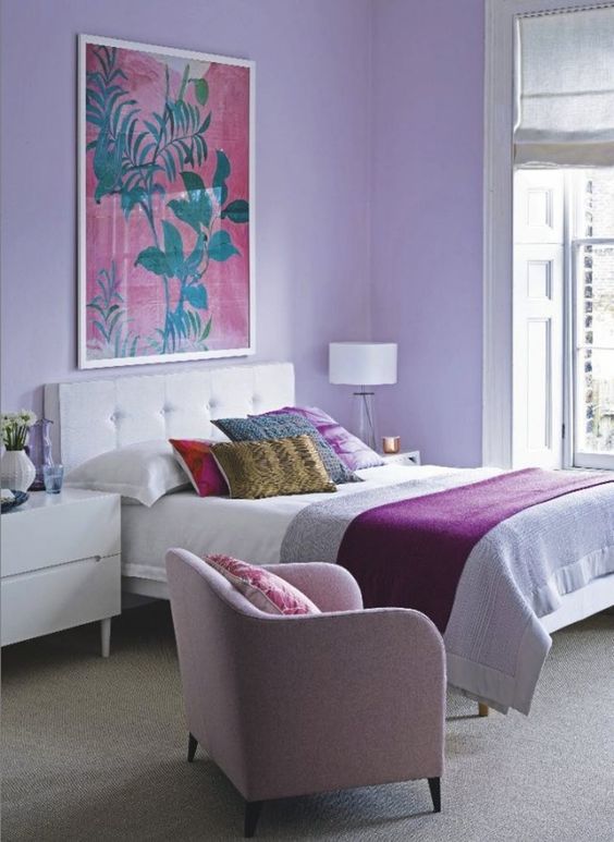a bright bedroom with lilac walls, a pink chair and bright bedding and pillows is a great place to wake up