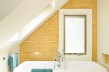 04 a small attic bathroom with a statement sunny yellow tile wall that makes it more welcoming
