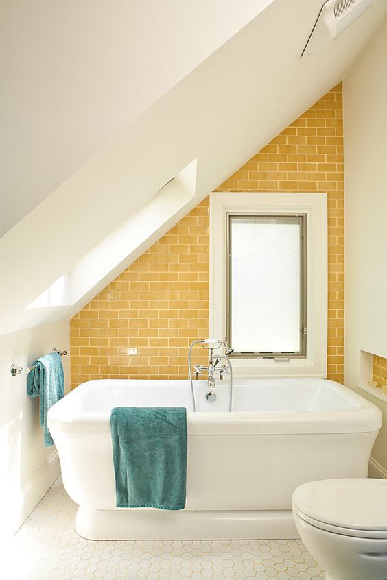 a small attic bathroom with a statement sunny yellow tile wall that makes it more welcoming