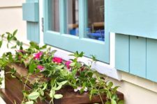 04 a stained slatted wood window box with fresh flowers adds interest to the light blue shutters