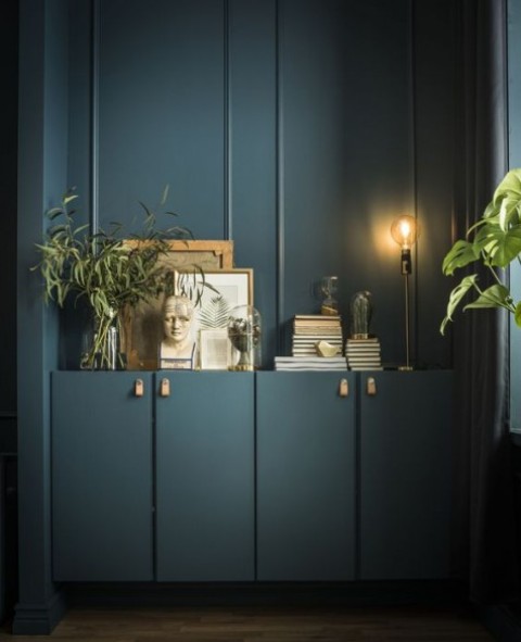 teal painted Ivar cabinets with leather pulls attached to the matching wall create a continuous space