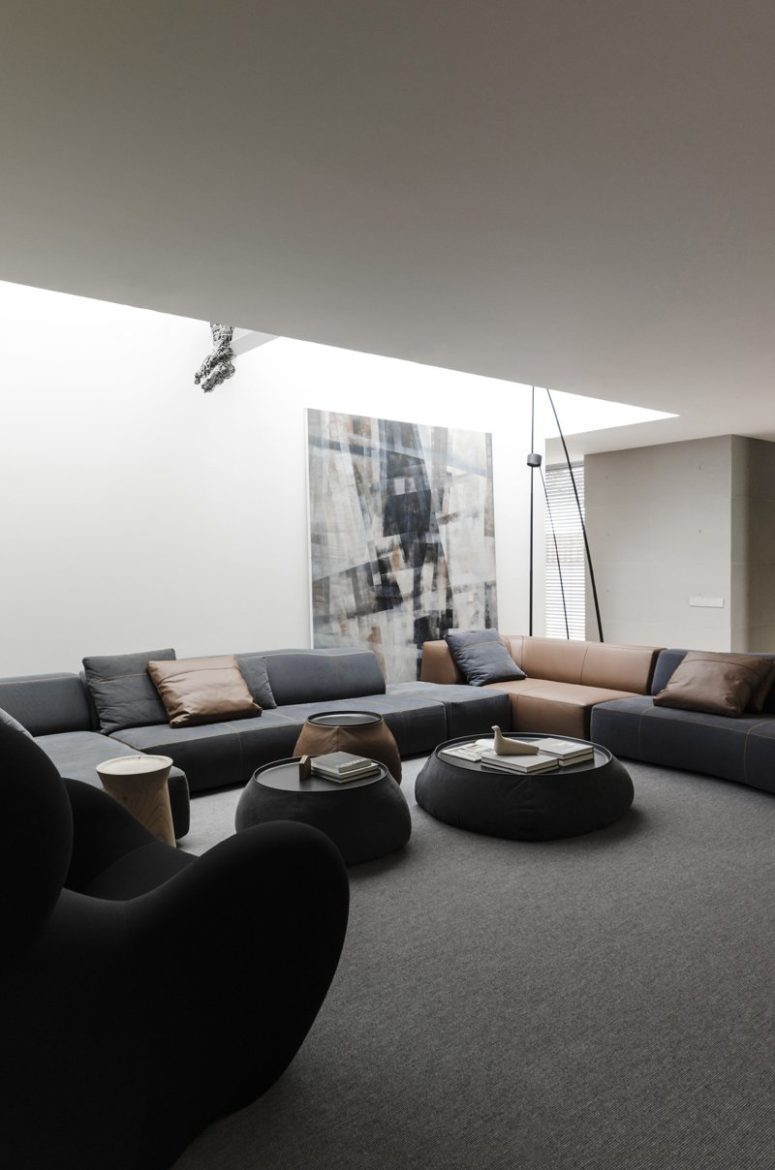 The living room is a gorgeous contemporary space in black and brown, with a large L-shaped sofa and round tables