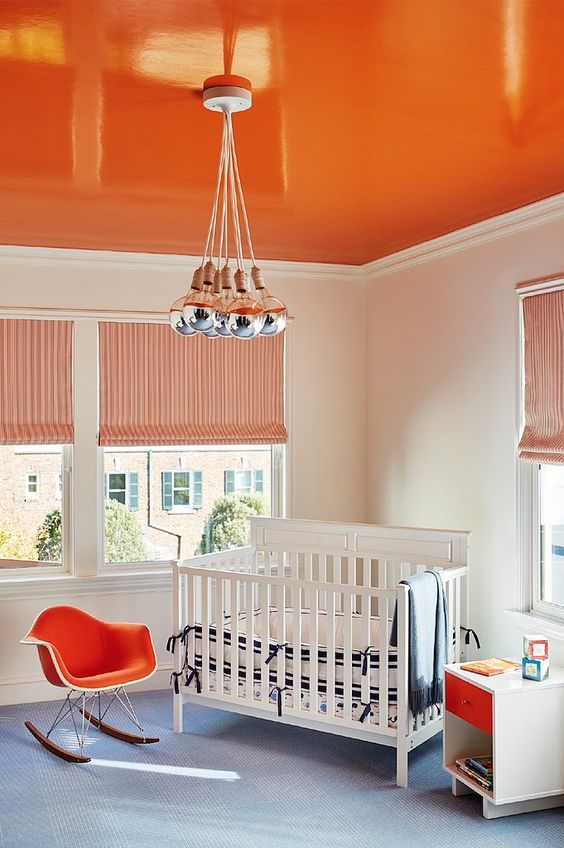 A bright orange ceiling, a matching chair and drawer to create a bold and welcoming kid's room