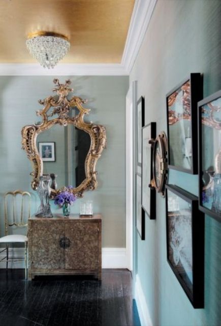a chic aqua entryway done with a gold ceiling and a vintage frame mirror plus a unique vanity