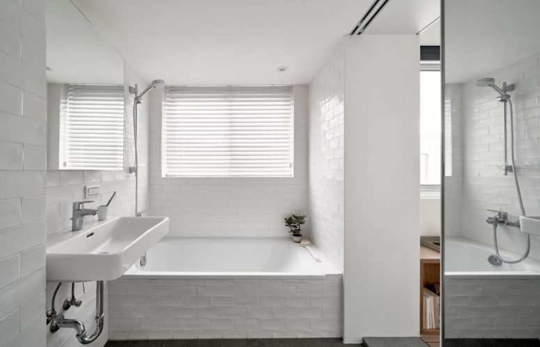 The bathroom is clad with white tiles, there's a covered window to have natural light yet privacy