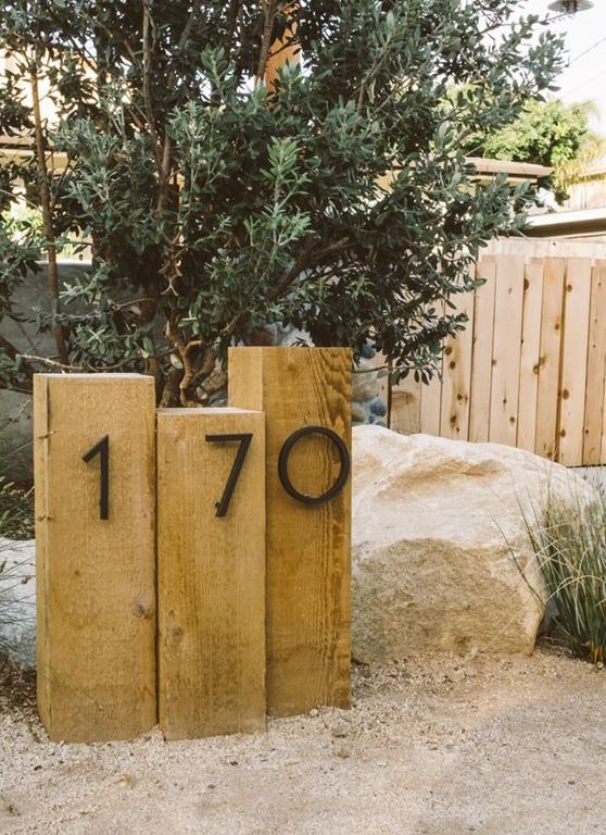 wooden posts with metal house numbers integrated right into the landscape is a stylish idea for a modern home