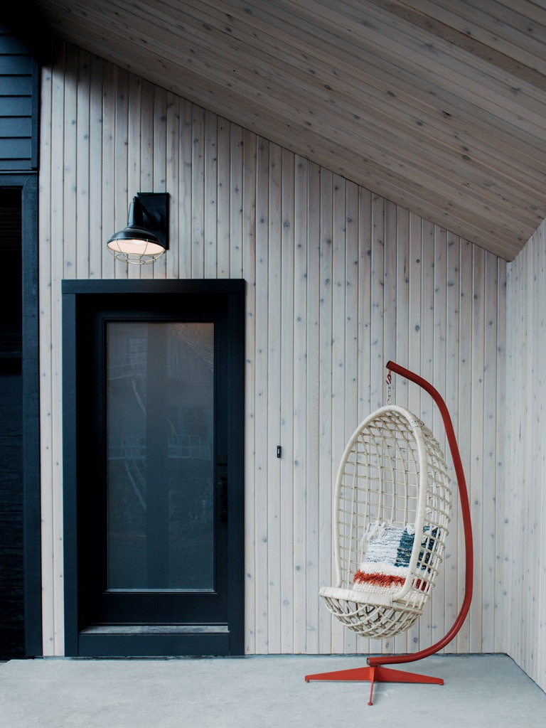 The porch is clad with light-colored pine and there's a catchy pendant chair