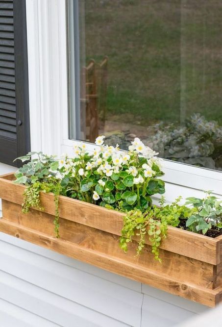 a cedar window box planter with much greenery and white flowers looks cute and rustic