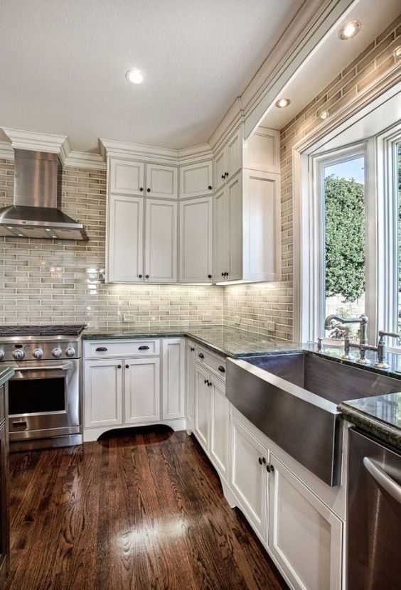 rich-colored hardwood floors and white wood cabinets are a chic and classic kitchen combo