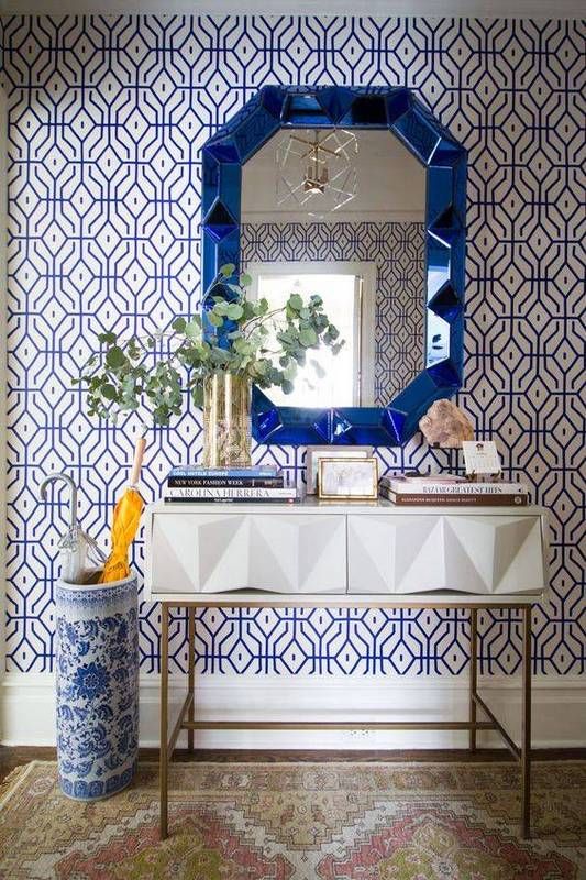 a bold blue printed wallpaper statement wall and a matching urn and mirror for a wow effect