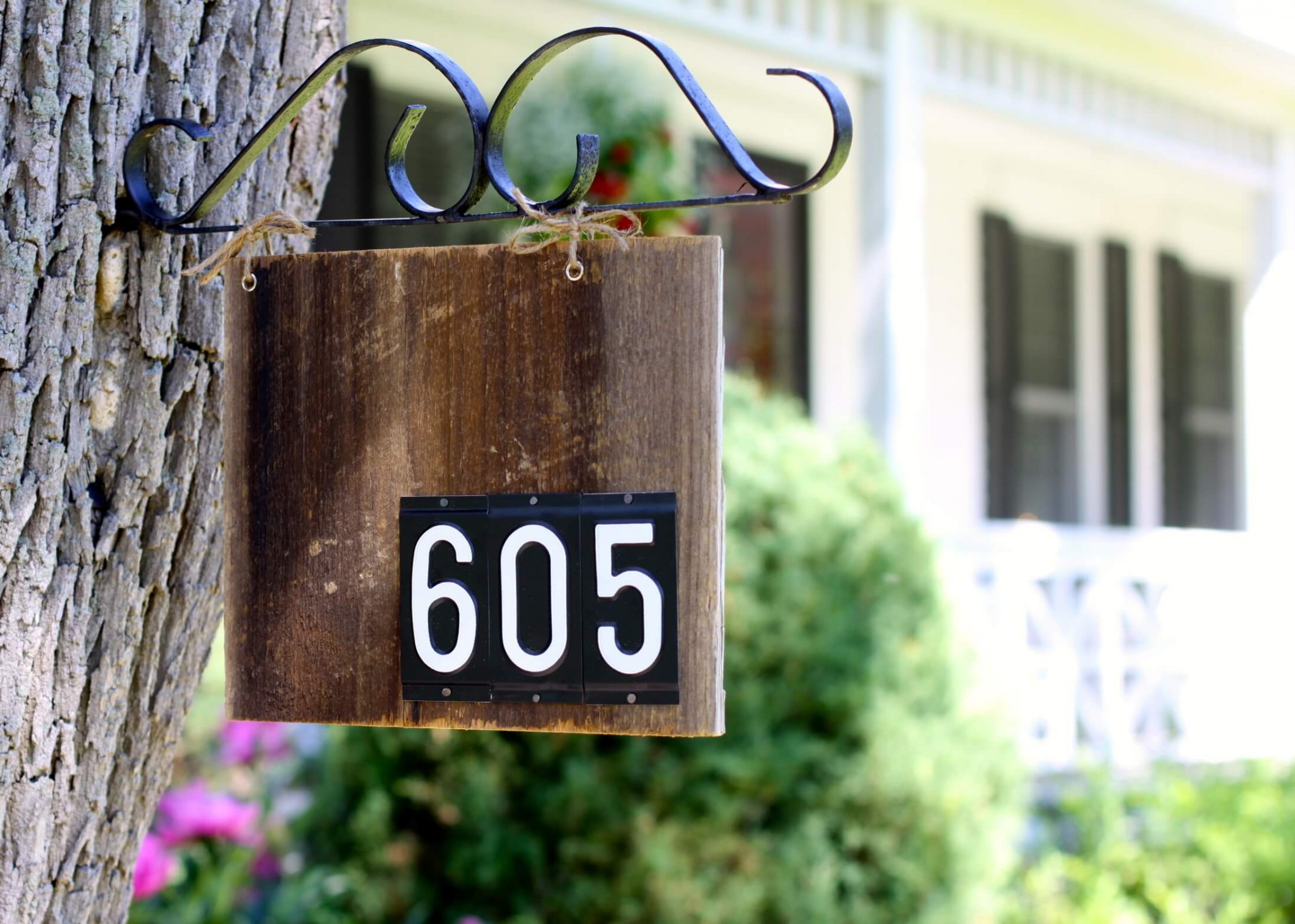 A house number sign hanging from a tree is a stylish vintage inspired idea for any home