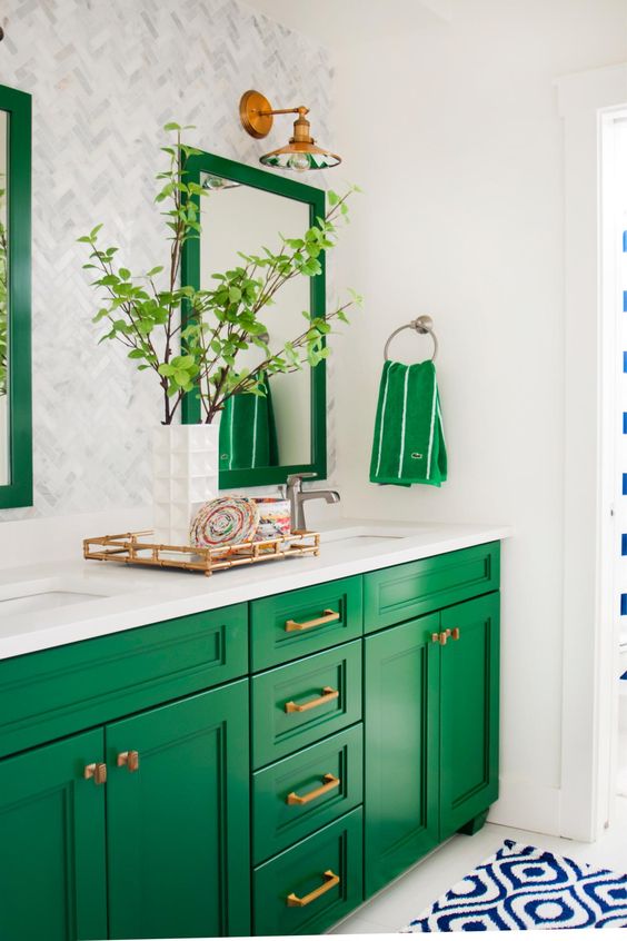 a bright emerald vanity accented with brass handles and matching frames and towels over the vanity