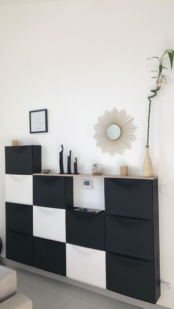 a contemporary living room console made up of several IKEA Trones units in black and white and with a wooden tabletop