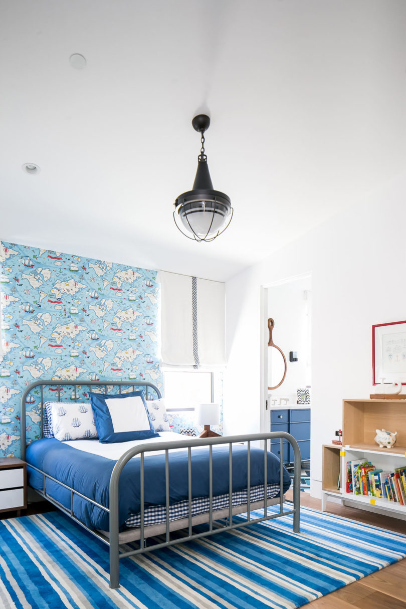 The kid's bedroom is done with a nautical feel, with catchy wallpaper and rugs