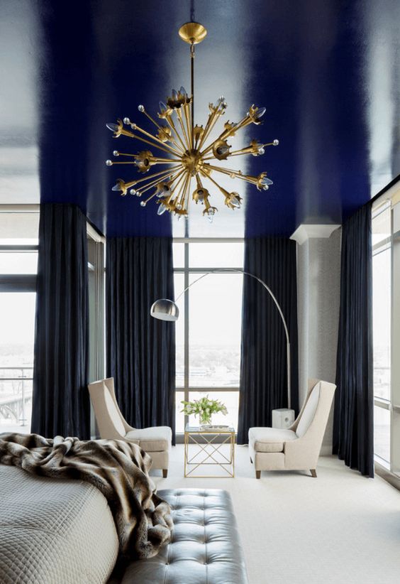 A shiny navy ceiling is a cool way to add a touch of color and a moody feel to the monochromatic bedroom