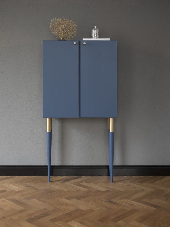 a very chic and refined hack of an Ivar cabinet in navy, with tall gold and navy legs and gold knobs