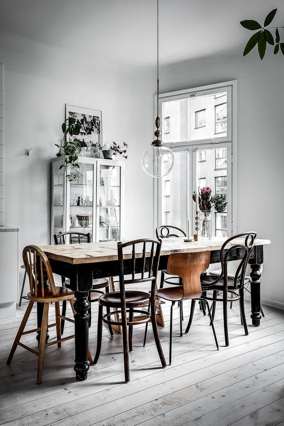 A gorgeous vintage Scandinavian dining space with mismatching wood chairs and a table plus a light colored wood floor