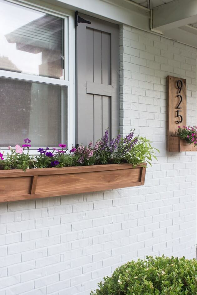 a simple and modern wooden flower box with bold purple and pink blooms adds a contemporary feel