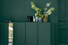 17 dark green Ivar cabinets with gold legs in front of a matching wall create a gorgeous moody space