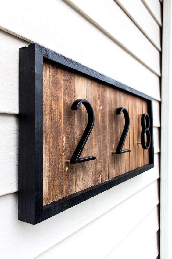 a modern house number sign with wood shims and black metal numbers and frame looks stylish and very laconic