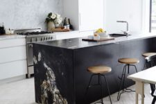 19 a black kitchen island with a stone waterfall countertop contrasts the space and makes a statement