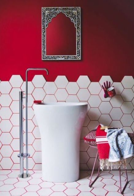 a hot red statement wall and hot red grout that accents the hex tiles on the wall and floors