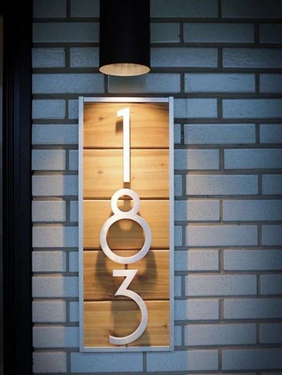 A modern house number sign of light colored wood, white painted numbers and frame for a bold look