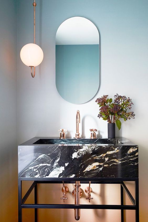 an edgy black marble vanity resting on a blackened steel vanity and accessorized with copper touches