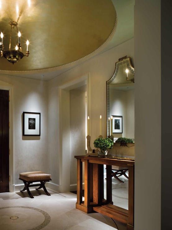a contemporary and refined entryway spruced up with a round gold ceiling medallion and a chic chandelier