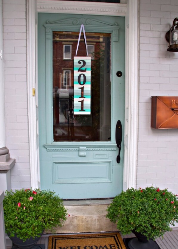 A colorful paint stick sign with house numbers hanging on the front door   a cool idea instead of a wreath on the front door