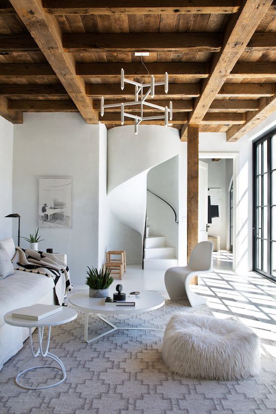 a rustic wooden ceiling with beams is a warm feature that adds coziness to this all-white space