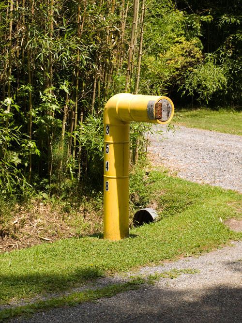 a submarine-inspired mailbox in industrial style, in a bold yellow shade and with house numbers written on it