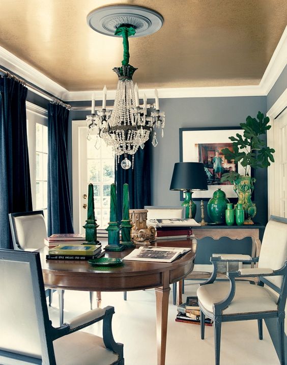 an elegant dining room with refined furniture, a sophisticated chandelier and a gold ceiling