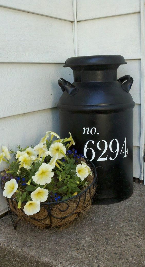 a large black milk churn with white house numbers on your porch is a nice idea to show your address with a rustic feel