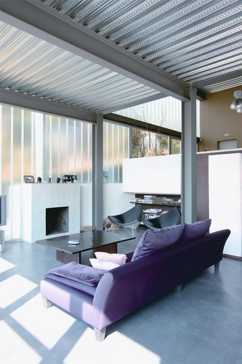 a chic contemporary living room with a corrugated ceiling with metal beams that contrast the furniture