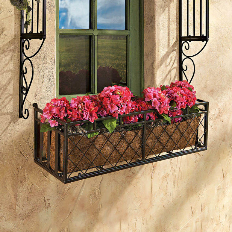 a black metal criss-cross window box for potted plants and flowers allows changing the plants whenever you want